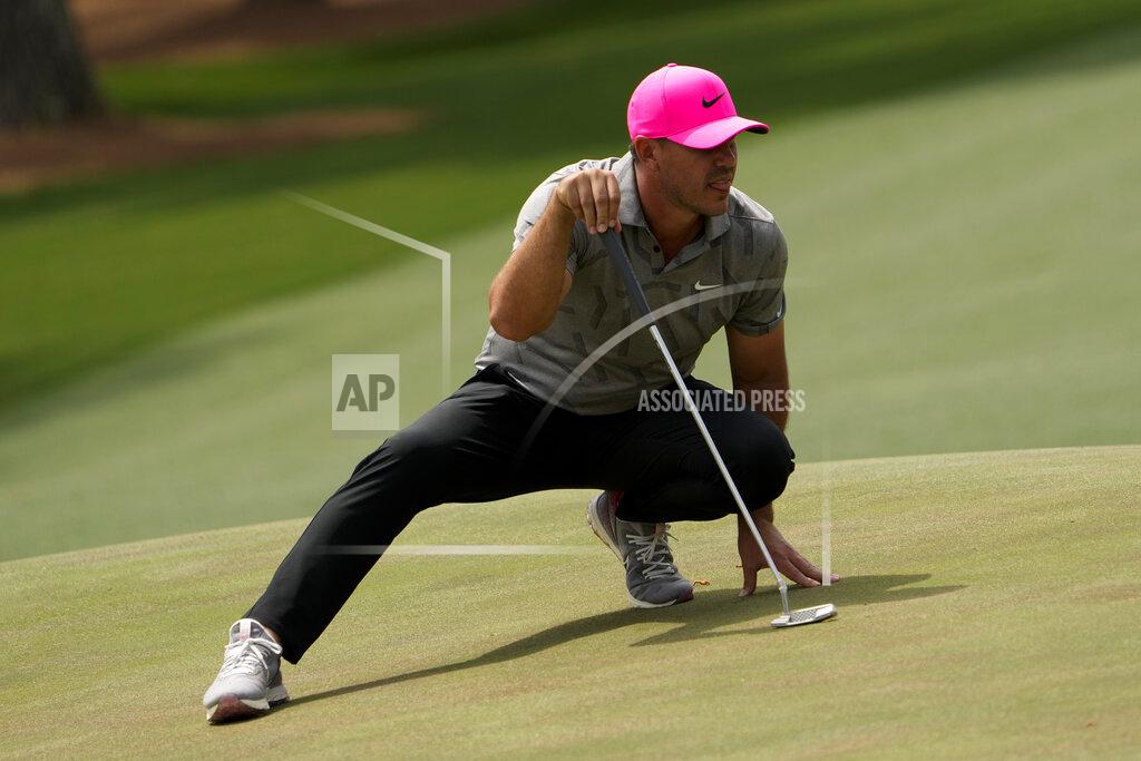 David J. Phillip Brooks Koepka stretches to line up a putt on the 14th green during the first round of the Masters golf tournament on Thursday, April 8, 2021, in Augusta, Ga. (AP Photo/David J. Phillip)