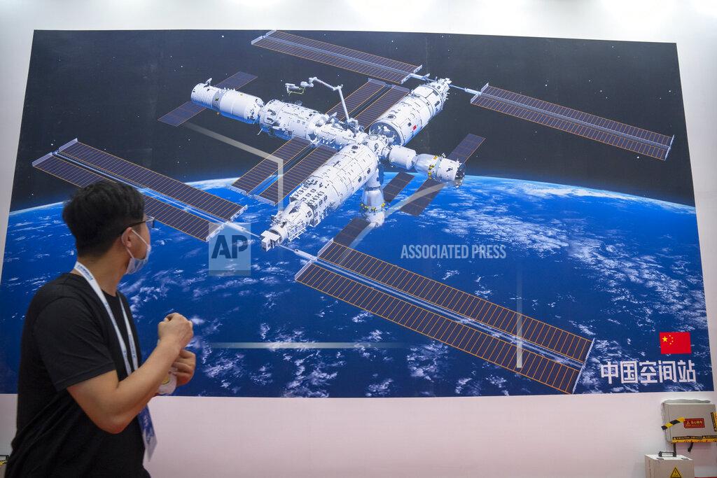 Mark Schiefelbein A visitor looks at a mural showing an artist's rendering of China's space station at the World Robot Conference in Beijing, Saturday, Sept. 11, 2021. Three Chinese astronauts have departed from the country’s orbiting space station in preparation for returning to Earth after 90 days in orbit, the national space agency reported Thursday, Sept. 16, 2021. (AP Photo/Mark Schiefelbein)