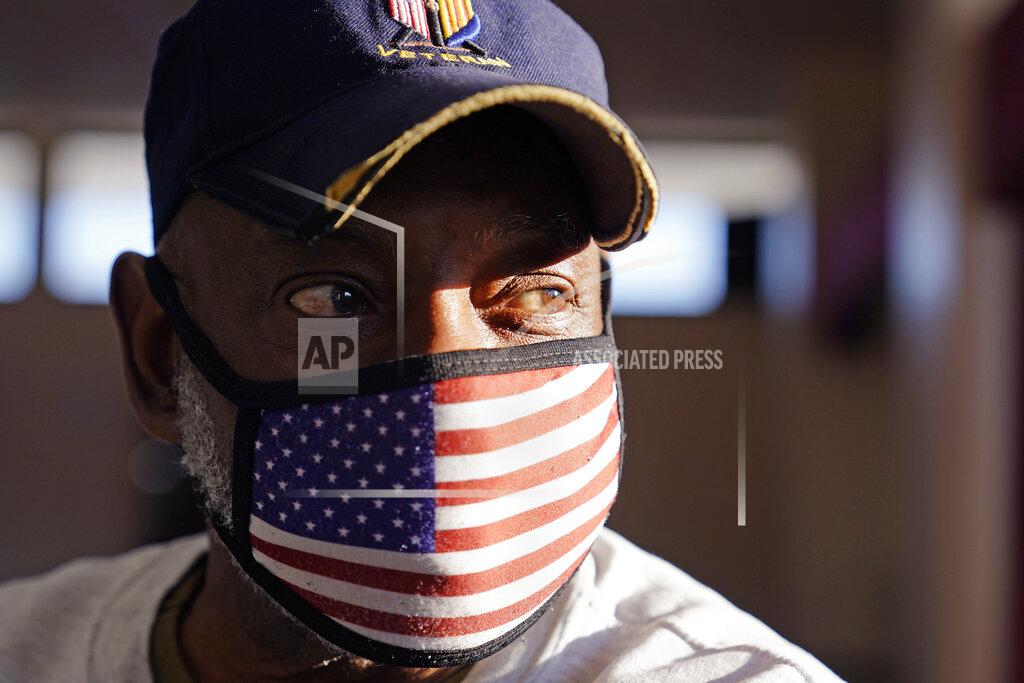 Charles Krupa Bob Workman, a board of directors member at Veterans of Foreign Wars Post #1018, wears a stars and stripes protective mask and a Vietnam veteran hat as he prepares for a meeting, Monday, March 15, 2021, in Boston. Local bars and halls run by VFW and American Legion posts have fallen on hard times during the coronavirus pandemic. Organizers say many risk permanent closure after states ordered them, like other bars and halls, to shutter last spring. (AP Photo/Charles Krupa)