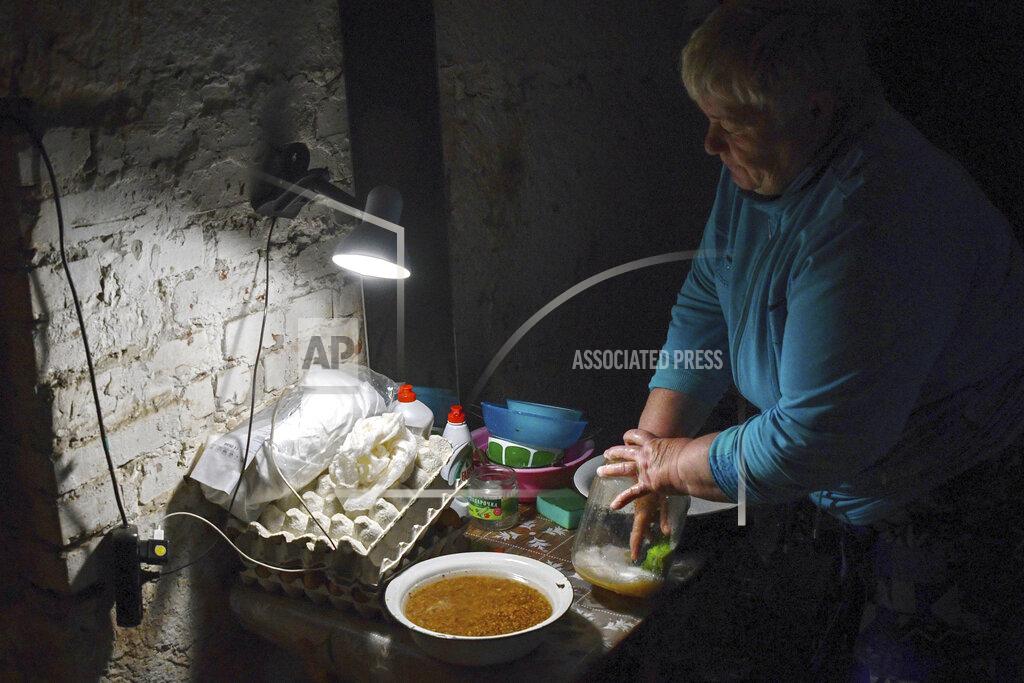 Andriy Andriyenko An Ukrainian woman washes dishes in the basement of a building used as bomb shelter in Soledar, Donetsk region, Ukraine, Tuesday, May 24, 2022. No matter where Ukrainians live, the 3-month-old war never seems to be far away. Those in towns and villages near the front lines hide in basements from constant shelling, struggling to survive with no electricity or gas — and often no running water. (AP Photo/Andriy Andriyenko)