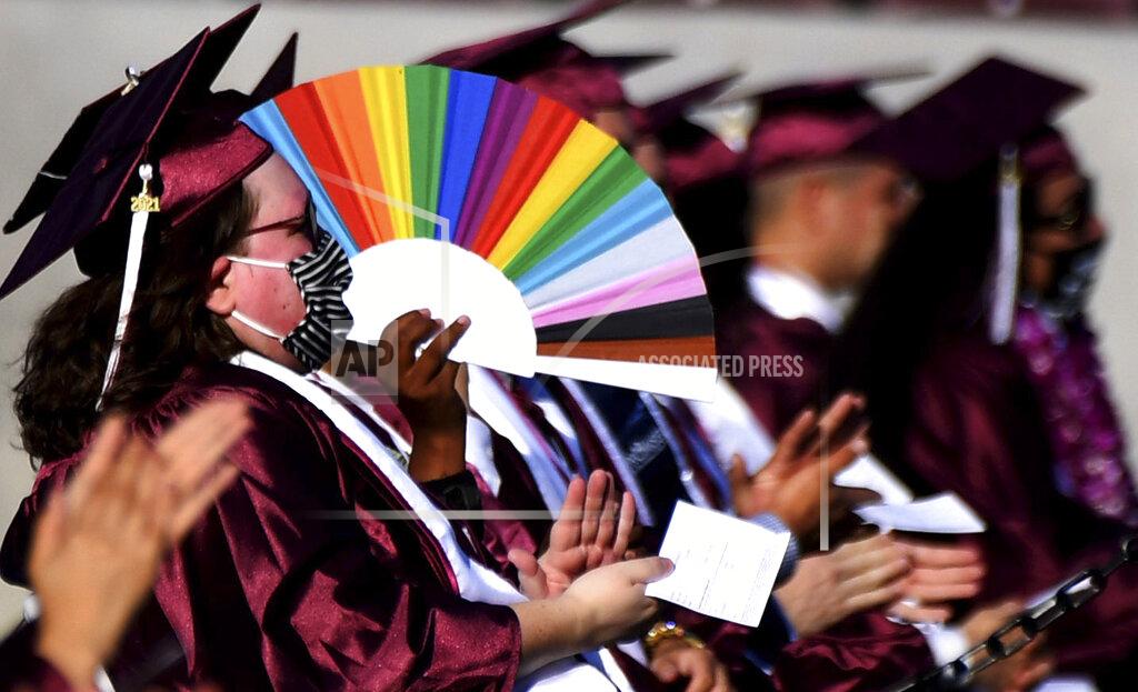 Keith Birmingham A student uses a colorful fan for shade on a hot day during the Mount Sac graduation at Hilmer Lodge Stadium in Walnut, Calif., Friday, June 11, 2021. (Keith Birmingham/The Orange County Register via AP)