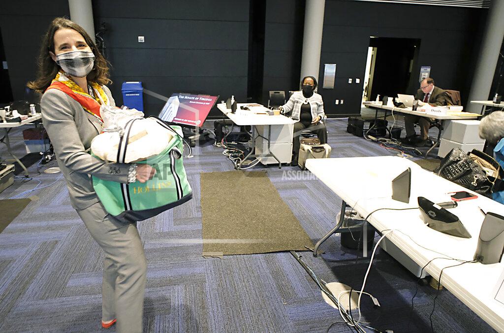 Bob Brown Sen. Jennifer Boysko, D-Fairfax, carries a load of frozen meals she had in her hotel room to put in a freezer in the members' lounge before the floor session of the Virginia Senate, which is meeting inside the Science Museum of Virginia in Richmond, Va., Saturday, Feb. 27, 2021. (Bob Brown/Richmond Times-Dispatch via AP)