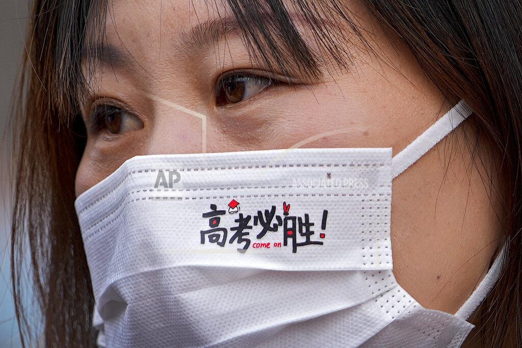 Andy Wong A woman wearing a face mask with the words "Gaokao, must win" as students take part on the first day of China's national college entrance examinations, known as the gaokao, in Beijing, Monday, June 7, 2021WLD. More than 10 million high school students throughout China will take the two days annual college entrance exams which start on Monday to Tuesday, according to the state media report. (AP Photo/Andy Wong)