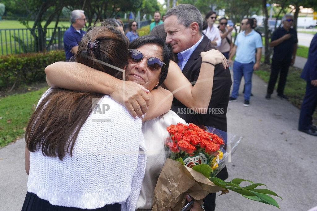 Wilfredo Lee FILE - Andrea Langesfeld, center, and her husband Pablo, right rear, parents of Nicole "Nicky" Langesfeld, who died in the Surfside, Fla., condo collapse, are hugged as they attend a ceremony to unveil a sign for "Nicky Langesfeld Place" on June 22, 2022, in Doral, Fla. A judge has given final approval Thursday, June 23, 2022, to a settlement of more than $1 billion for victims of the collapse of a Florida beachfront condominium. Ninety-eight people died when the 12-story Champlain Towers South suddenly collapsed. The decision comes one day before the one-year anniversary of the disaster in the Miami suburb of Surfside. (AP Photo/Wilfredo Lee, File)