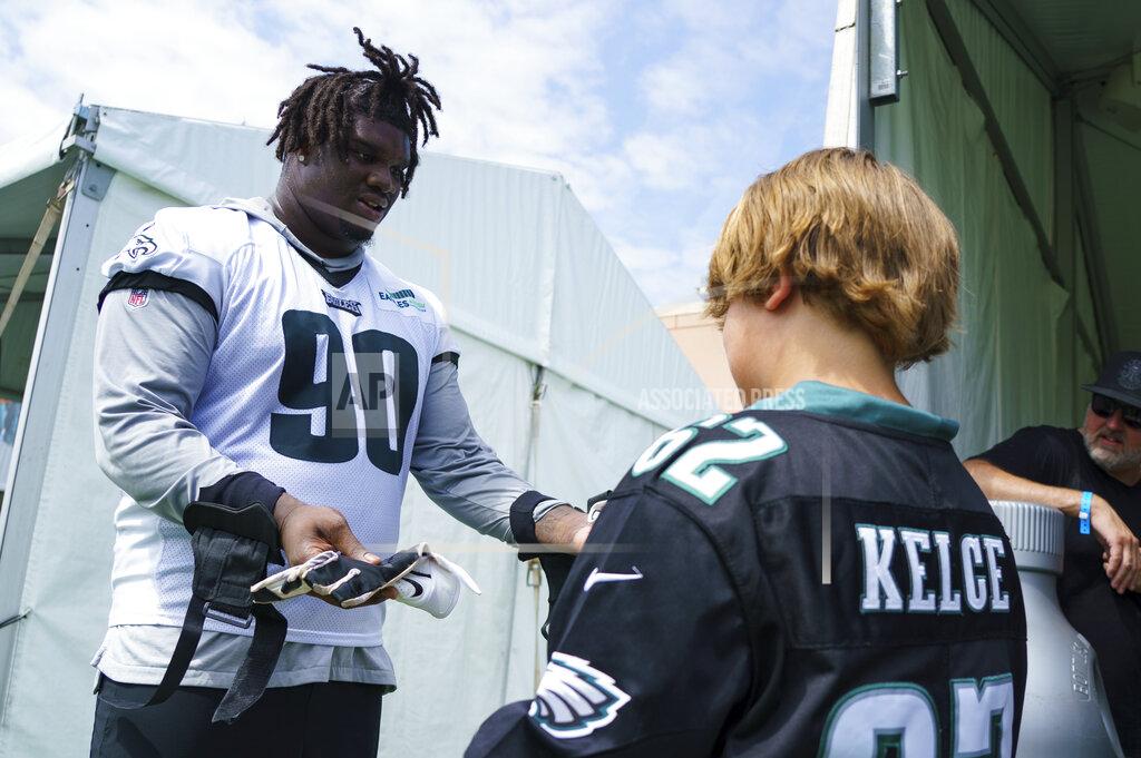 Chris Szagola Philadelphia Eagles' Jordan Davis, left, hands his gloves to a couple of fans, right, following practice at NFL football team's training camp, Wednesday, July 27, 2022, in Philadelphia. (AP Photo/Chris Szagola)