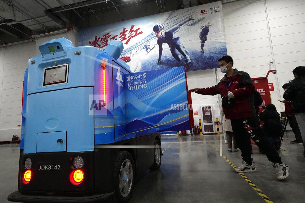 Ng Han Guan A worker opens the door of a delivery robot at the Main Distribution Center built to provide logistic support for the upcoming Beijing Winter Olympics and Paralympics in Beijing, China, Thursday, Dec. 9, 2021. The 34-meter-tall building has started operation at the end of last year to receive, store and distribute furniture, sport and technical equipment, and other materials for the current test events and next year's Winter Games. (AP Photo/Ng Han Guan)