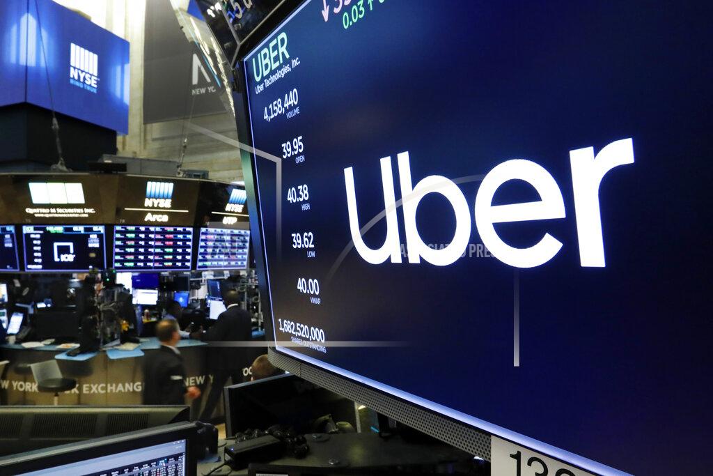 FILE - The logo for Uber appears above a trading post on the floor of the New York Stock Exchange, Thursday, May 30, 2019. Uber has reported that it whittled its losses at the end of a topsy-turvy year. In 2020, the ride-hailing service was forced to rely more heavily on its food-delivery service. That's because the pandemic dramatically reduced the number of people willing to hop into a car driven by a stranger. The fourth-quarter results announced Wednesday, Feb. 10, 2021 drew a picture of a company making strides in its attempt to recover from a staggering blow delivered last March. (AP Photo/Richard Drew, file)