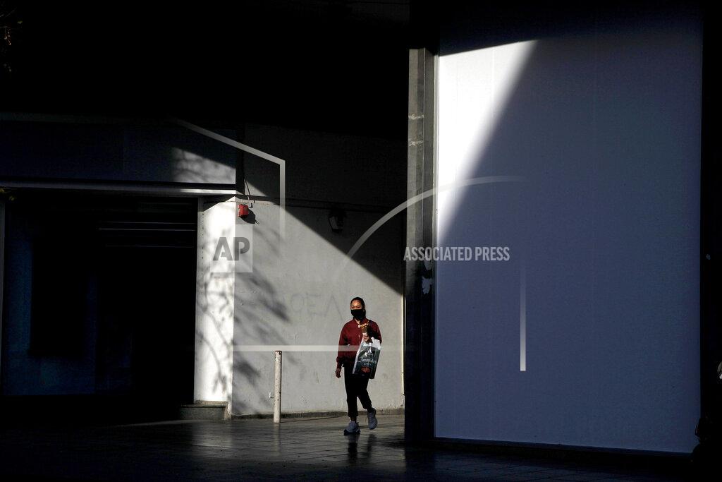 Petros Karadjias A woman wearing face mask walks at a shopping street in central Nicosia, Friday, Jan. 8, 2021. Cyprus is returning to lockdown mode for the remainder of the month with daytime restrictions on movement and a shuttering of schools after the country's health minister conceded that a raft of tough measures already in place including a night-time curfew weren't enough to curtail the spread of the coronavirus. (AP Photo/Petros Karadjias)
