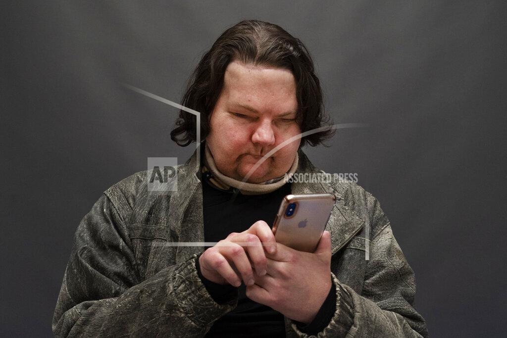 Mark Lennihan Joe DiMeo uses his cellphone while posing for a portrait, Monday, Jan. 25, 2021, in New York, six months after an extremely rare double hand and face transplant. Almost six months after a rare face and hands transplant, Joe DiMeo is relearning how to smile, blink, pinch and squeeze. The 22-year-old New Jersey resident had the operation last August, two years after being badly burned in a car crash.(AP Photo/Mark Lennihan)