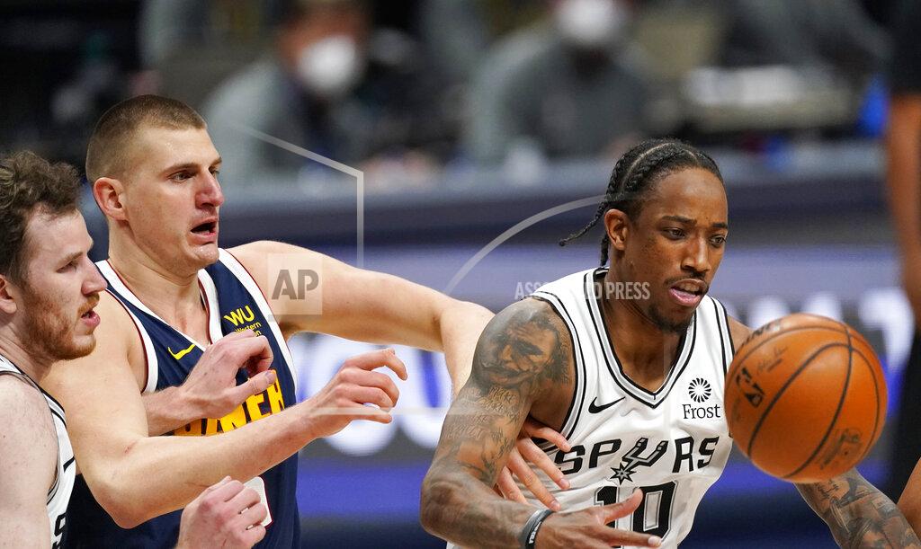 David Zalubowski San Antonio Spurs forward DeMar DeRozan, right, fights for control of the ball with Spurs center Jakob Poeltl, left, and Denver Nuggets center Nikola Jokic, center, in the second half of an NBA basketball game Friday, April 9, 2021, in Denver. (AP Photo/David Zalubowski)