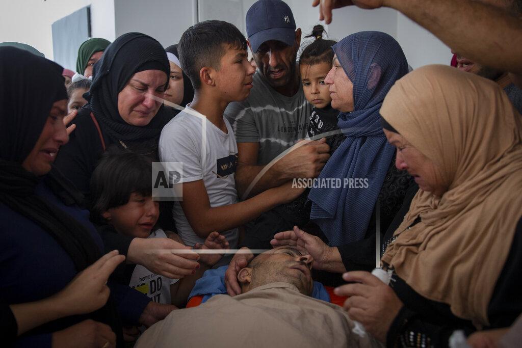 Majdi Mohammed Palestinian women mourn around the body of Raed Jadallah, 39, who was killed by Israeli forces at the western entrance of his village while returning from work in the early hours of Wednesday morning, during his funeral, in the West Bank village of Beit Ur al-Tahta, Wednesday, Sep. 1, 2021. (AP Photo/Majdi Mohammed)