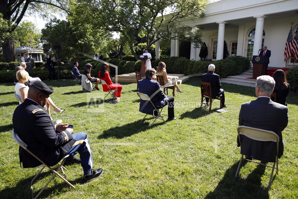 President Donald Trump listens as Sister Eneyda Martinez, with Poor Sisters of St. Joseph, at left podium, speaks during a White House National Day of Prayer Service in the Rose Garden of the White House, Thursday, May 7, 2020, in Washington. (AP Photo/Alex Brandon)
