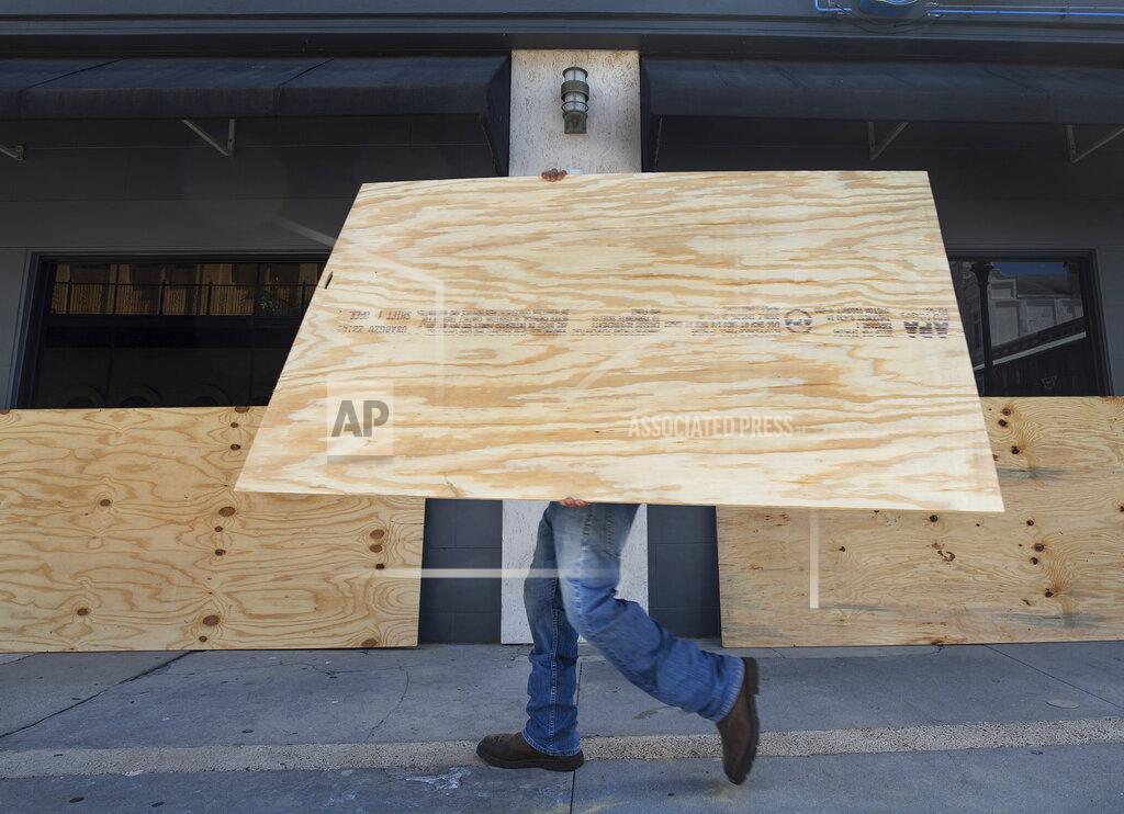 Stuart Villanueva Miguel Andrade Jr. carries plywood to board up the windows at Rudy and Paco Restaurant and Bar in downtown Galveston, Tuesday, Aug 25, 2020. Local businesses continued to make preparations for Hurricane Laura's arrival along the gulf coast. (Stuart Villanueva/The Galveston County Daily News via AP)