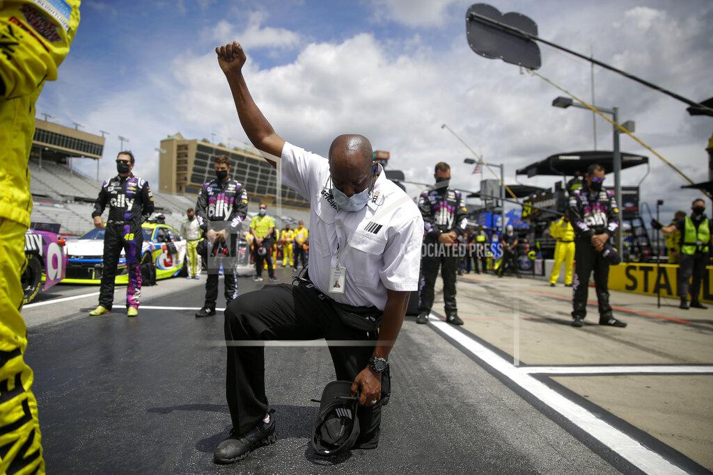 Brynn Anderson FILE - In this June 7, 2020, file photo, a NASCAR official kneels during the national anthem before a NASCAR Cup Series auto race at Atlanta Motor Speedway in Hampton, Ga. The largest auto racing series in North America for years had specific guidance for its teams to stand, helmetless and hatless, with right hands over the heart during the anthem. That language was removed less than a month ago as NASCAR goes through a reckoning of its own. (AP Photo/Brynn Anderson, File)