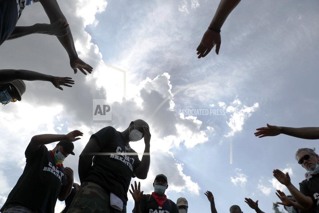 Andrew Harnik FILE - In this Saturday, June 6, 2020 file photo, Pastor Trevor Kinlock with Metropolitan Seventh-day Adventist Church, center, is prayed over as demonstrators protest in Washington, over the death of George Floyd, a Black man who was in police custody in Minneapolis. Floyd died after being restrained by Minneapolis police officers. (AP Photo/Andrew Harnik)