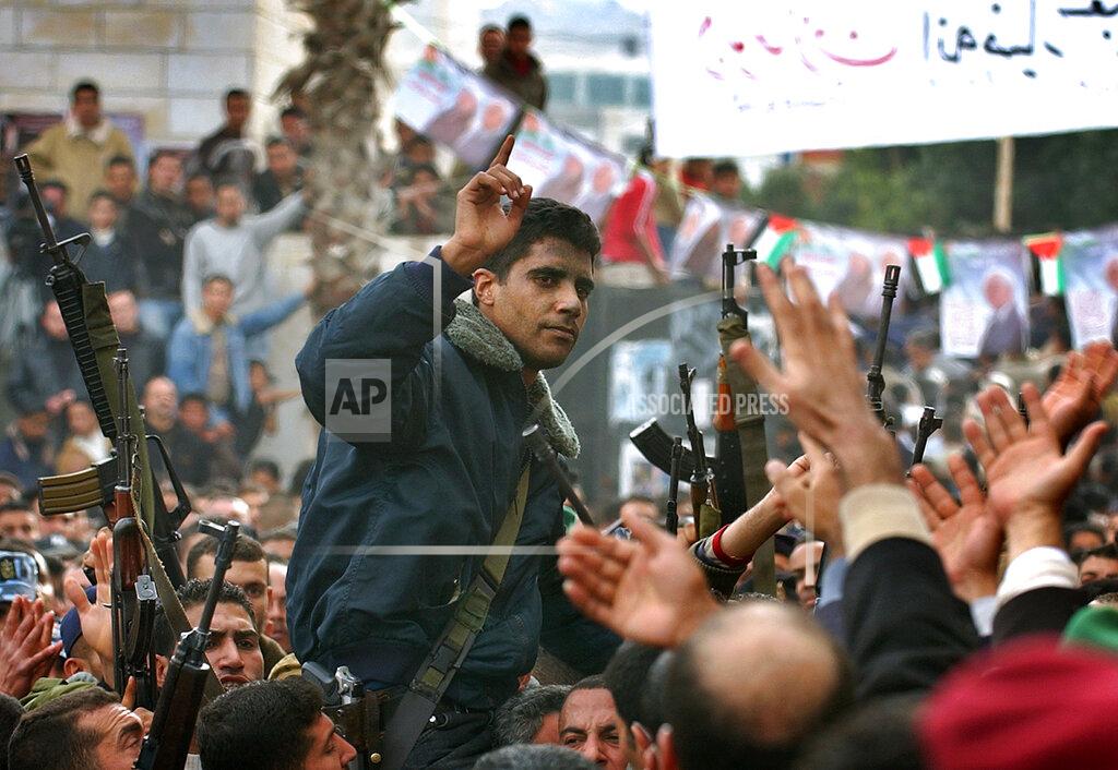 Nasser Nasser FILE - In this Dec. 30, 2004 file photo, Zakaria Zubeidi, then leader in the Al Aqsa Martyrs Brigade in the West Bank, is carried by supporters during a presidential elections campaign rally in support of Mahmoud Abbas, in the West Bank town of Jenin. For nearly two decades, Zubeidi has been an object of fascination for Israelis and Palestinians alike, who have seen his progression from a child actor to a swaggering militant, to the scarred face of a West Bank theater promoting “cultural resistance” to Israeli occupation. In his latest act, he has emerged as one of Israel's most wanted fugitives after tunneling out of a high-security prison on Monday, Sept. 6, 2021, with five other Palestinian militants. (AP Photo/Nasser Nasser, File)