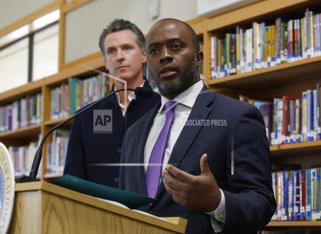 Rich Pedroncelli FILE — In this Oct. 31, 2019, file photo, state Superintendent of Public Instruction Tony Thurmond answers a reporter's question during a visit with California Gov. Gavin Newsom, background, to Blue Oak Elementary School, in Cameron Park, Calif. California's schools superintendent said Wednesday, May 20, 2020, he expects classes for the state's 6 million students to resume as usual in late August or September. (AP Photo/Rich Pedroncelli, File)