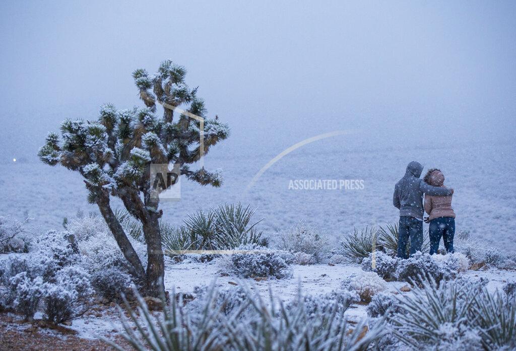 Chase Stevens James Minner, of Las Vegas, left, and Candace Reid, of Albuquerque, N.M., watch as snow falls around the overlook at the Red Rock Canyon National Conservation Area outside of Las Vegas on Wednesday, Feb. 20, 2019. (Chase Stevens/Las Vegas Review-Journal via AP)
