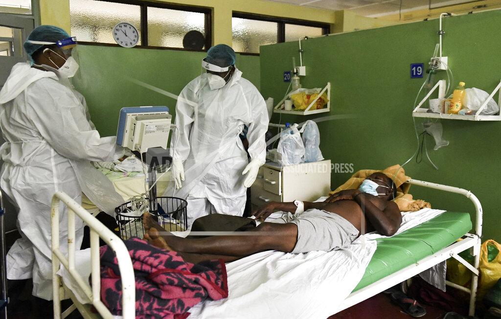 A health worker attends to a COVID-19 patient at Queen Elizabeth Central Hospital COVID-19 male ward in Blantyre, Malawi on Saturday, Jan. 30, 2021. Malawi faces a resurgence of COVID-19 that is overwhelming the southern African country where a presidential residence and a national stadium have been turned into field hospitals in efforts to save lives. (AP Photo/Thoko Chikondi)
