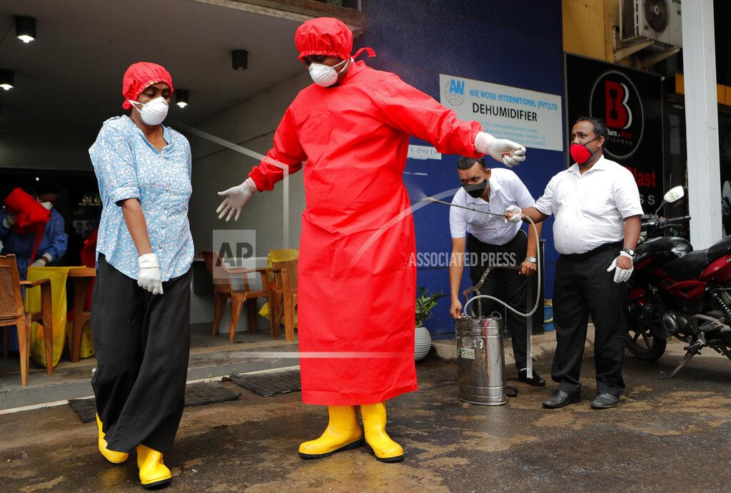 Eranga Jayawardena Sri Lankan Municipal health workers spray disinfectant to another colleague who conducted blood tests for COVID-19 antibody tests at a market place in Colombo, Sri Lanka, Friday, June 26, 2020. (AP Photo/Eranga Jayawardena)