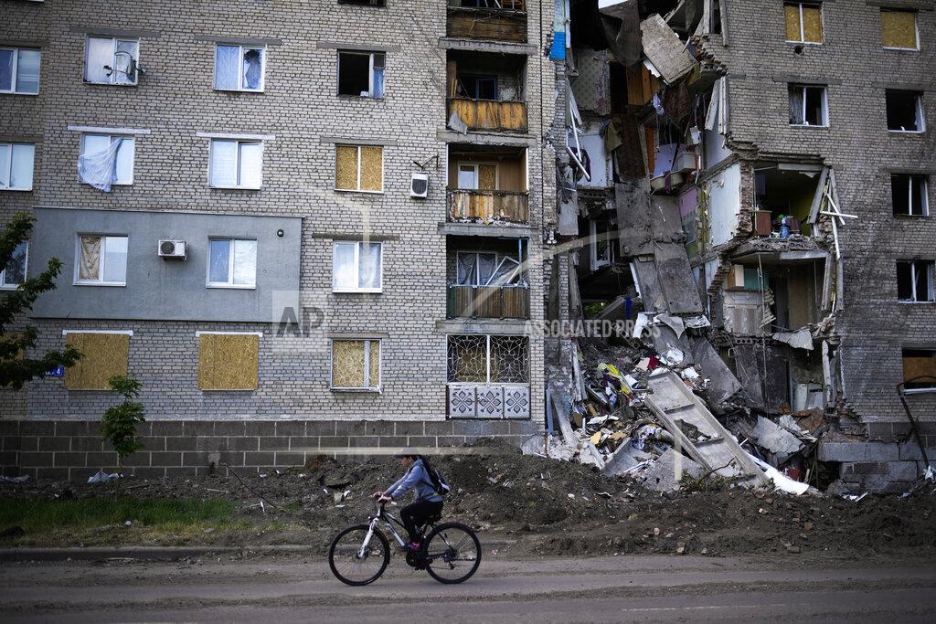 Francisco Seco A woman rides a bicycle past a residential building heavily damaged in a Russian bombing in Bakhmut, eastern Ukraine, Tuesday, May 24, 2022. The town of Bakhmut has been coming under increasing artillery strikes, particularly over the last week, as Russian forces try to press forward to encircle the city of Sieverodonetsk to the northeast. (AP Photo/Francisco Seco)
