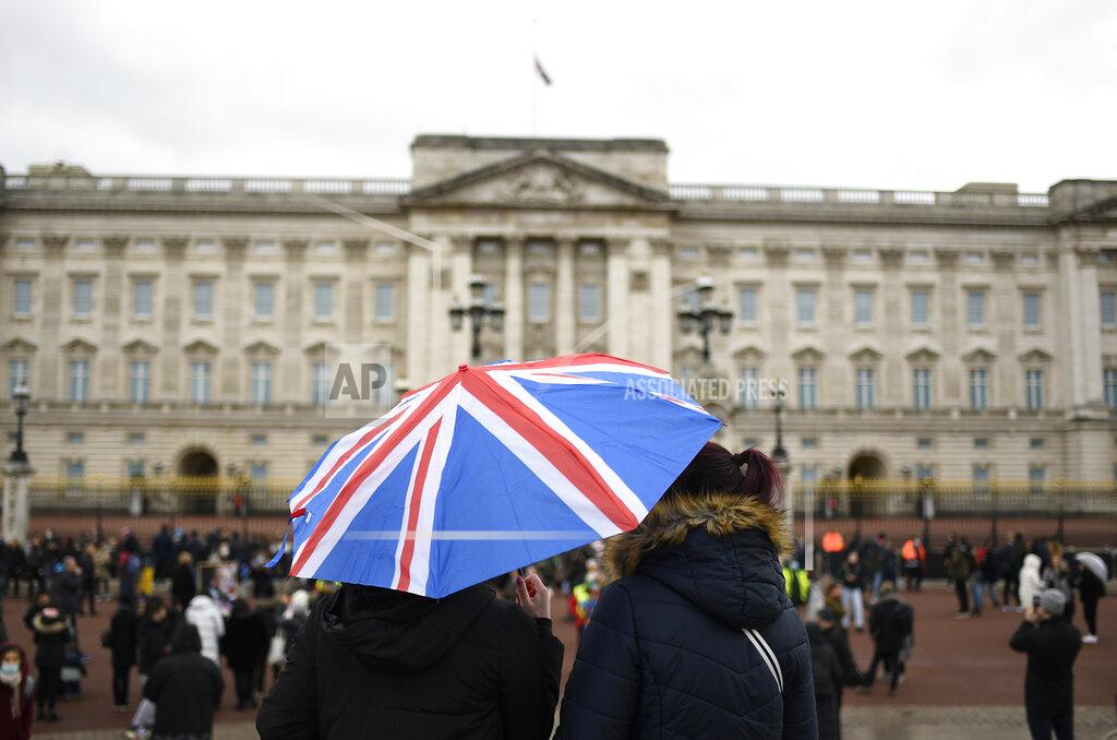 Alberto Pezzali A couple stand under an umbrella will the Union flag on it outside Buckingham Palace in London, a day after the death of Britain's Prince Philip, Saturday, April 10, 2021. Britain's Prince Philip, the irascible and tough-minded husband of Queen Elizabeth II who spent more than seven decades supporting his wife in a role that mostly defined his life, died on Friday. (AP Photo/Alberto Pezzali)