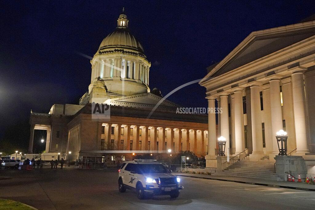 Ted S. Warren FILE - In this Jan. 10, 2021 file photo, a Washington State Patrol vehicle drives past the Insurance Building with the Legislative Building in the background at the Capitol in Olympia, Wash., the night before the opening of the 2021 legislative session. The 2021 session of the Washington Legislature ended Sunday, April 25 and lawmakers had no shortage of weighty topics to consider while having to conduct their work amid a pandemic that meant most meetings and votes were conducted remotely. The Capitol building was also closed to the public since last year due to the COVID-19 pandemic, and was surrounded by security fencing and national guard members at times due to fears of protests. (AP Photo/Ted S. Warren, File)