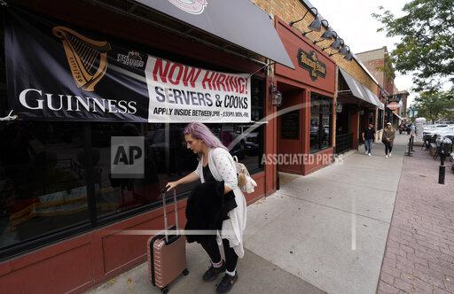 FILE - A traveller wheels her baggage past a now hiring sign outside a bar and restaurant Saturday, Oct. 9, 2021, in Sioux Falls, S.D. America’s employers slowed the pace of their hiring in November, adding 210,000 jobs, the lowest monthly gain in nearly a year. Friday, Dec. 3 report from the Labor Department also showed that the nation's unemployment rate tumbled from 4.6% to 4.2% evidence that many more people reported that they had a job. (AP Photo/David Zalubowski)