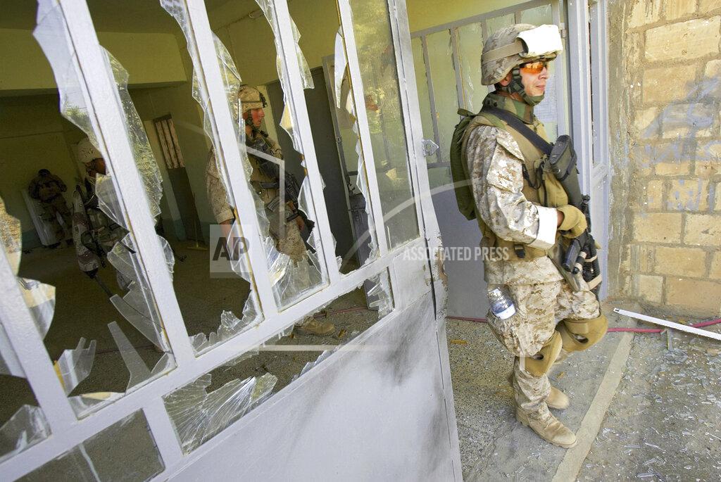 Jacob Silberberg FILE—This file photo from Aug. 6, 2005, shows U.S. Marine Staff Sgt. Brian Hamilton of Columbus, Ohio, from Lima Company of the 3rd Battalion, 25th Regiment as he exits after searching a school, in Parwana, near Haditha, Iraq. Days before, a nearby roadside bomb killed 14 Marines, many from this platoon, and a civilian interpreter on August 3, 2005. Some survivors and families of those killed had planned a 15-year reunion this weekend, but it had to be canceled amid restrictions for the COVID-19 pandemic. (AP Photo/Jacob Silberberg, File)