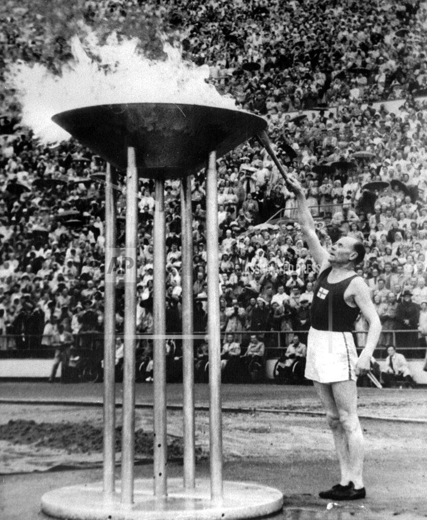 Olympic Pool Runner Paavo Nurmi, of Finland, lights the Olympic flame from the Olympic torch, during July 19, 1952, opening ceremony in Helsinki, Finland. (AP Photo)