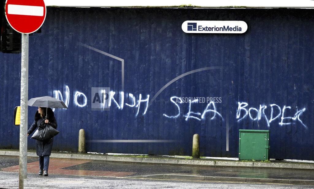 Peter Morrison A woman walks past past graffiti with the words 'No Irish Sea Border' in Belfast city centre, Northern Ireland, Wednesday, Feb. 3, 2021. Politicians from Britain, Northern Ireland and the European Union are meeting to defuse post-Brexit trade tensions that have shaken Northern Ireland’s delicate political balance. British Cabinet minister Michael Gove, European Commission Vice President Maros Sefcovic and the leaders of Northern Ireland’s Catholic-Protestant power-sharing government will hold a video conference to discuss problems that have erupted barely a month after the U.K. made an economic split from the 27-nation EU. (AP Photo/Peter Morrison)