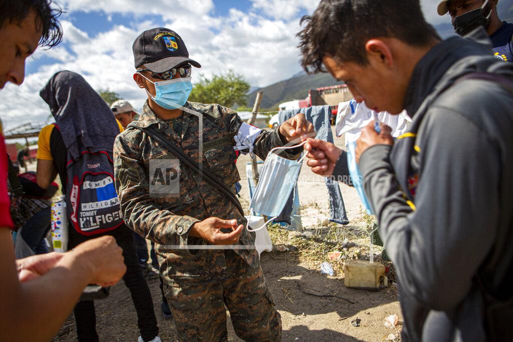 Oliver De Ros A member of the Guatemalan army hands a protective face mask to an Honduran migrant who has been detained at a police checkpoint on the border near Zacapa, Guatemala, Wednesday, Jan. 20, 2021. After a year of pandemic-induced paralysis, those in daily contact with migrants believe the flow north could return to the high levels seen in late 2018 and early 2019. The difference is that it would happen during a pandemic. (AP Photo/Oliver de Ros)