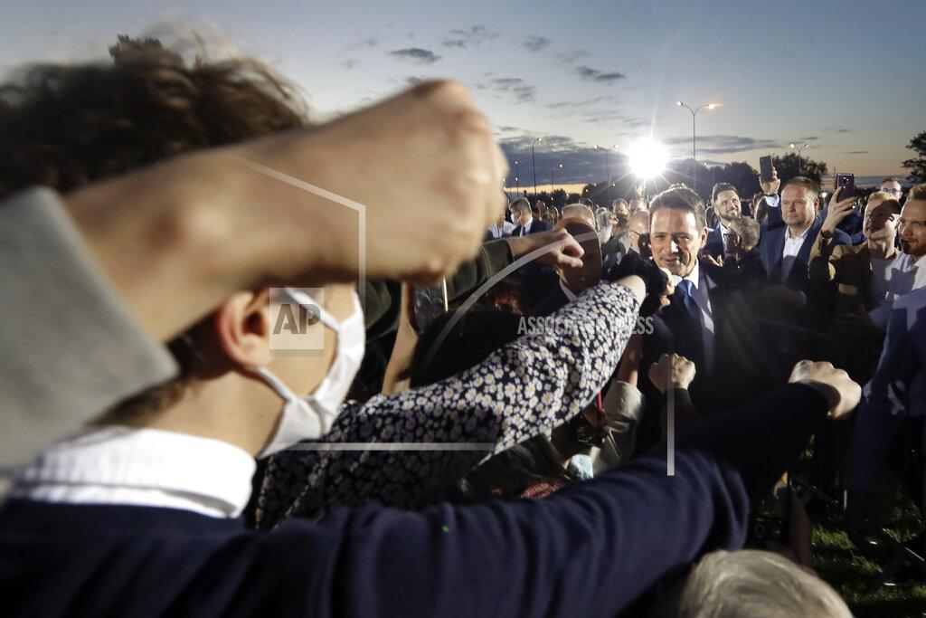 Petr David Josek Supporters stretch their hands to touch fists with Presidential candidate Rafal Trzaskowski, right, at the end of the election day in Warsaw, Poland, Sunday, July 12, 2020. Voting ended in Poland's razor-blade-close presidential election runoff between the conservative incumbent Andrzej Duda and liberal, pro-European Union Warsaw Mayor Rafal Trzaskowski with exit polls showing the election is too close to call. (AP Photo/Petr David Josek)