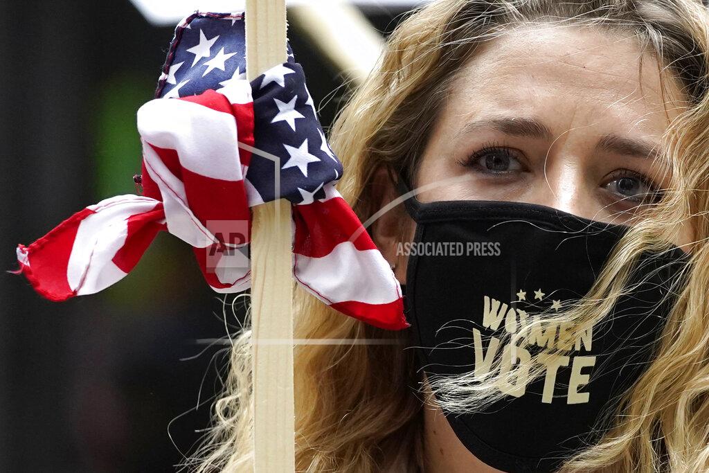 Nam Y. Huh Lindsey Schwartz wears a mask with a message as she holds a sign during the Women's March in downtown Chicago, Saturday, Oct. 17, 2020. Dozens of Women's March rallies were planned from New York to San Francisco to signal opposition to President Donald Trump and his policies, including the push to fill the seat of late Supreme Court Justice Ruth Bader Ginsburg before Election Day. (AP Photo/Nam Y. Huh)