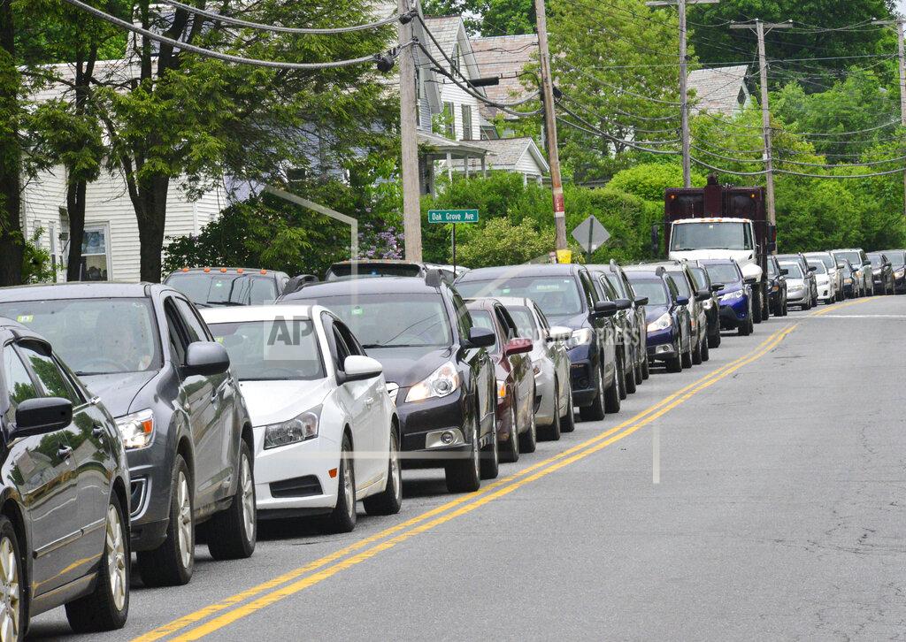 Kristopher Radder Hundreds of vehicles line up on South Main Street as they slowly make their way to Brattleboro Union High School, Wednesday, May 27, 2020, in Brattleboro, Vt., as members from the Vermont National Guard hand out free boxes of non-perishable food, along with produce, chicken, and dairy products at Farmers to Families Food Box Distribution site. (Kristopher Radder/The Brattleboro Reformer via AP)
