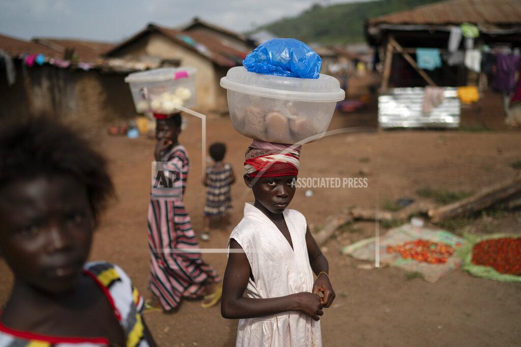 Leo Correa Isatu, 12, carries packets of rice flour to sell at Komao village, on the outskirts of Koidu, district of Kono, Sierra Leone, Sunday, Nov. 22, 2020. Sierra Leone closed its borders before the country had its first COVID-19 case. As a result, the country has seen only 2,434 confirmed cases and 74 deaths. Only 76 of those cases were confirmed in Kono district, but the economic toll here has brought many families already living on the edge to a breaking point. (AP Photo/Leo Correa)