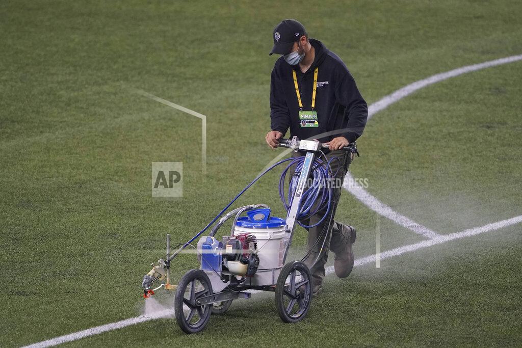 Ted S. Warren A field worker sprays a solvent to remove paint marking the goal box on the turf at CenturyLink Field following an MLS soccer match between the Seattle Sounders and Los Angeles FC, Friday, Sept. 18, 2020, in Seattle. The stadium is being prepared Sunday's NFL football game between the Seattle Seahawks and the New England Patriots. (AP Photo/Ted S. Warren)
