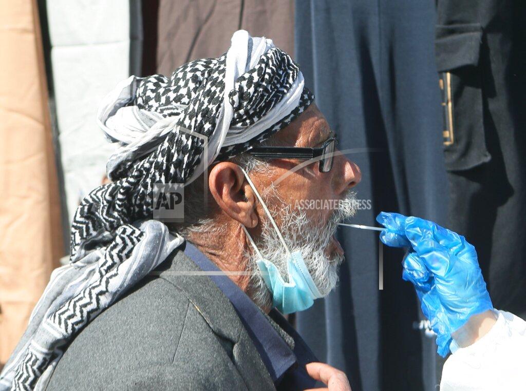 FILE -- In this Feb. 22, 2021 file photo health worker collects a saliva sample from a man for a polymerase chain reaction (PCR) coronavirus test at the Shurja market, in Baghdad, Iraq . Infectious disease experts are expressing concern about Pope Francis’ upcoming trip to Iraq, given a sharp rise in coronavirus infections there, a fragile health care system and the unavoidable likelihood that Iraqis will crowd to see the pontiff. (AP Photo/Khalid Mohammed)