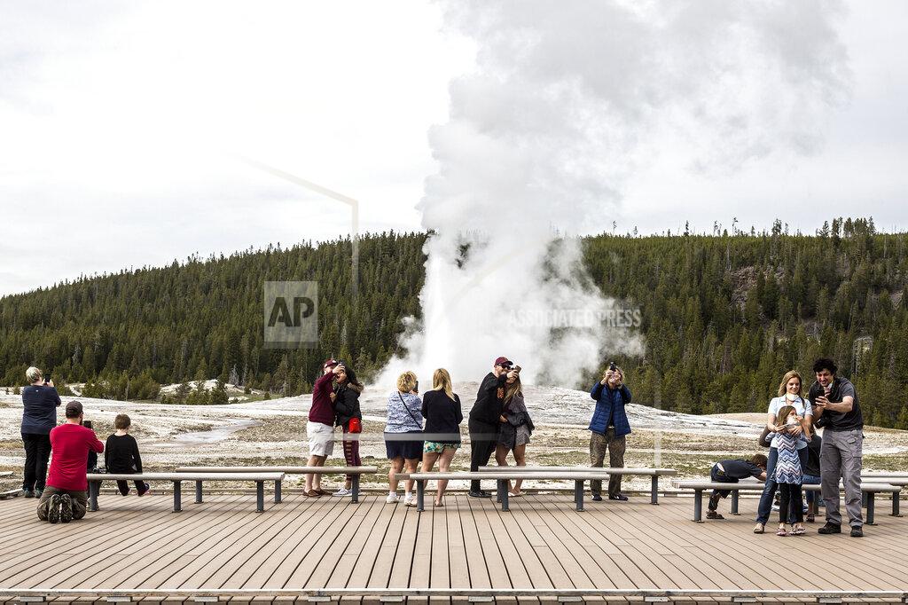 Ryan Dorgan FILE - In this May 18, 2020 photo, visitors watch as Old Faithful erupts on the day the park partially reopened after a two-month shutdown due to the coronavirus pandemic, at Yellowstone National Park, Wyo. Lawmakers have reached bipartisan agreement on an election-year deal to double spending on a popular conservation program and devote nearly $2 billion a year to improve and maintain national parks. (Ryan Dorgan/Jackson Hole News & Guide via AP, File)