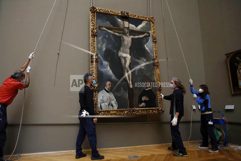 Thibault Camus Workers of the Louvre museum lift a painting called 'Christ on the Cross Adored by Two Donors' by Spanish painter El Greco, as it returns from an exhibition at the Chicago Institute, in the Louvre museum, in Paris, Tuesday, Feb. 9, 2021. The forced closure has granted museum officials a golden opportunity to carry out long-overdue refurbishments that were simply not possible with nearly 10 million visitors a year. (AP Photo/Thibault Camus)