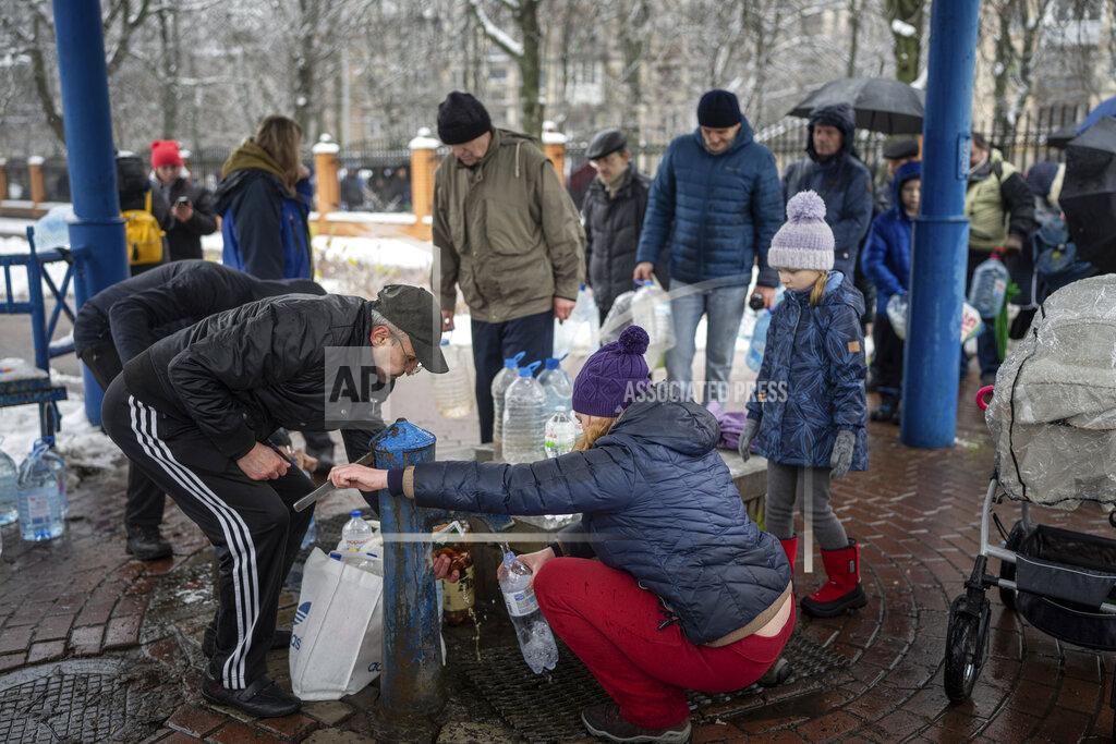 Evgeniy Maloletka People collect water, in Kyiv, Ukraine, Thursday, Nov. 24, 2022. Residents of Ukraine's bombed but undaunted capital clutched empty bottles in search of water and crowded into cafés for power and warmth Thursday, switching defiantly into survival mode after new Russian missile strikes a day earlier plunged the city and much of the country into the dark. (AP Photo/Evgeniy Maloletka)
