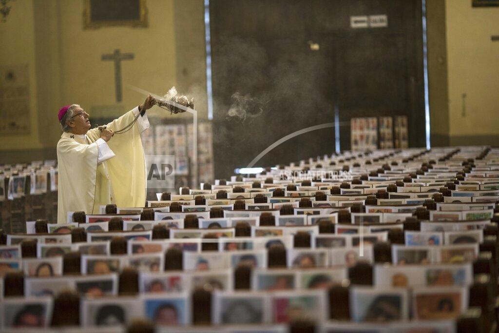 Rodrigo Abd The Archbishop of Lima Carlos Castillo swings a censer over several of the more than 4 thousand portraits of COVID-19 victims during the Corpus Christi Mass at the Cathedral of Lima, Peru, Sunday, June 14, 2020. (AP Photo/Rodrigo Abd)