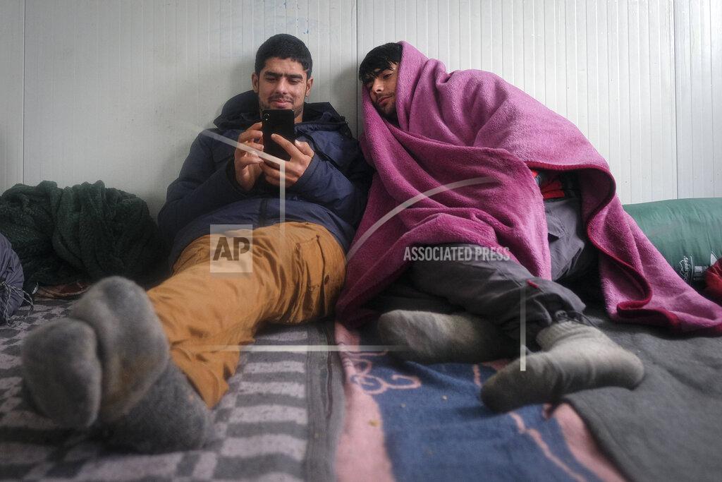 Kemal Softic Migrants look at a mobile phone at the Lipa camp, outside Bihac, Bosnia, Monday, Jan. 11, 2021. Aid workers say migrants staying at a camp in northwestern Bosnia have complained or respiratory and skin diseases after spending days in make-shift tents and containers amid freezing weather and snow blizzards. Most of the hundreds of migrants at the Lipa facility near Bosnia's border with Croatia on Monday have been accommodated in heated military tents following days of uncertainty after a fire gutted most of the camp on Dec. 23. (AP Photo/Kemal Softic)