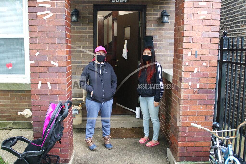 Noreen Nasir In this May 14, 2020 photo, Erendira Martinez and her daughter stand outside their home in the Little Village neighborhood of Chicago. Chicago’s Little Village neighborhood is known as the heart of Mexican culture in the city. It’s also located in the zip code area with one of the highest rates of positive coronavirus cases in the city. Both Martinez and her daughter, along with Martinez' husband, tested positive for COVID-19. All have since recovered. (AP Photo/Noreen Nasir)