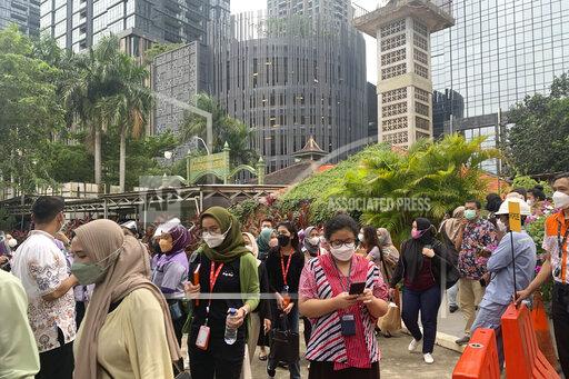 People wait outside as they have to evacuate their office buildings following an earthquake, at the main business district in Jakarta, Indonesia, Friday, Jan. 14, 2022. A powerful earthquake shook parts of Indonesia's main island of Java on Friday, causing buildings in the capital to sway, but there were no immediate reports of serious damage or casualties. Officials said there was no danger of a tsunami. (AP Photo/Tatan Syuflana)