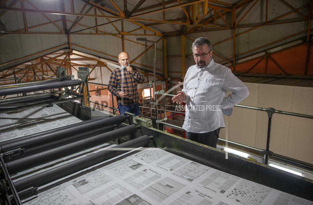 Visar Kryeziu Agron Bajrami, front, editor-in-chief of Koha daily newspaper joined by administrator of Koha printing house, Nexhmedin Berisha, inspect the last issue of the printed newspaper in the rotogravure printing machine, near the capital Pristina, Wednesday, April 28, 2021. The printing presses stopped running at the start of the pandemic in Kosovo. The country's five dailies all stopped printing physical newspapers and turned into online media portals. But these do not reach all the people as before, and many fear they prioritise speed over accuracy. (AP Photo/Visar Kryeziu)