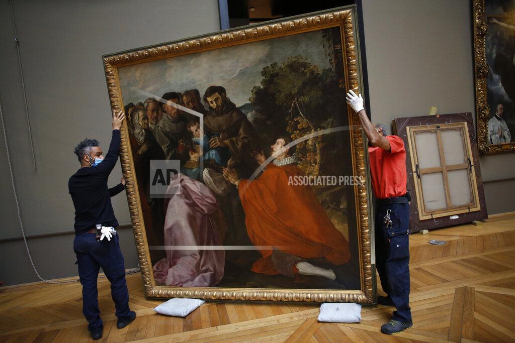 Thibault Camus Workers handle the painting called 'The Healing of Saint Bonaventure as a Child by Saint Francis' by Spanish painter Francisco de Herrera, in the Louvre museum, in Paris, Tuesday, Feb. 9, 2021. The forced closure has granted museum officials a golden opportunity to carry out long-overdue refurbishments that were simply not possible with nearly 10 million visitors a year. (AP Photo/Thibault Camus)