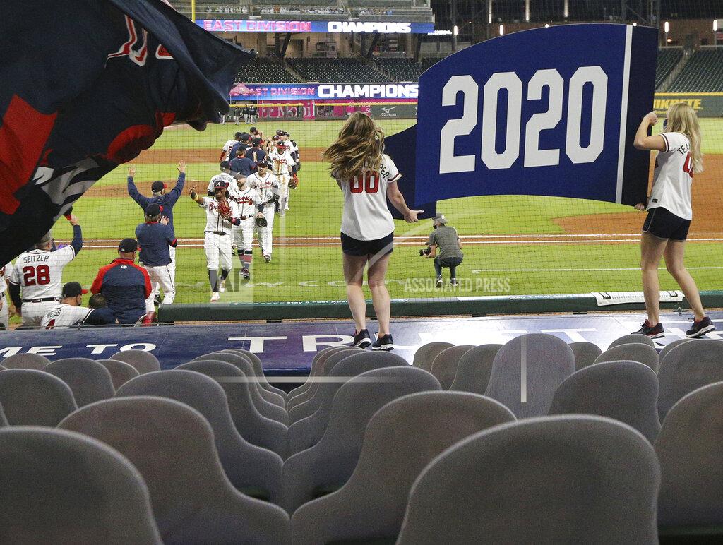 Curtis Compton Cutout fans and two cheerleaders holding the 2020 pennant are the only ones looking on as the Atlanta Braves celebrate clinching their third consecutive National League East title with a victory over the Miami Marlins in a baseball game on Tuesday, Sept. 22, 2020, in Atlanta. (Curtis Compton/Atlanta Journal-Constitution via AP)