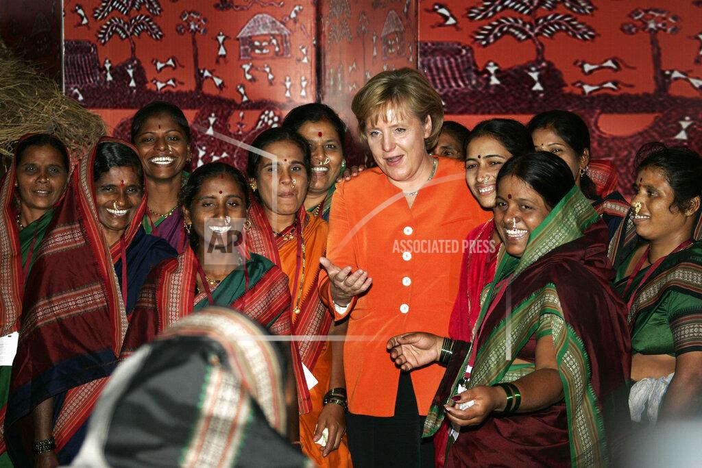 Herbert Knosowski FILE - In this Wednesday, Oct. 31, 2007, file photo, German Chancellor Angela Merkel, center, asks a woman, front, to join a group photo with Indian country women during her visit to the NABARD-Bank in Mumbai, India. On trips to Africa, the Middle East and Asia, Merkel has often made a point of visiting women’s rights projects. She has always stressed that giving women in poor countries better access to education and work is key to those nations' development. (AP Photo/Herbert Knosowski, File)
