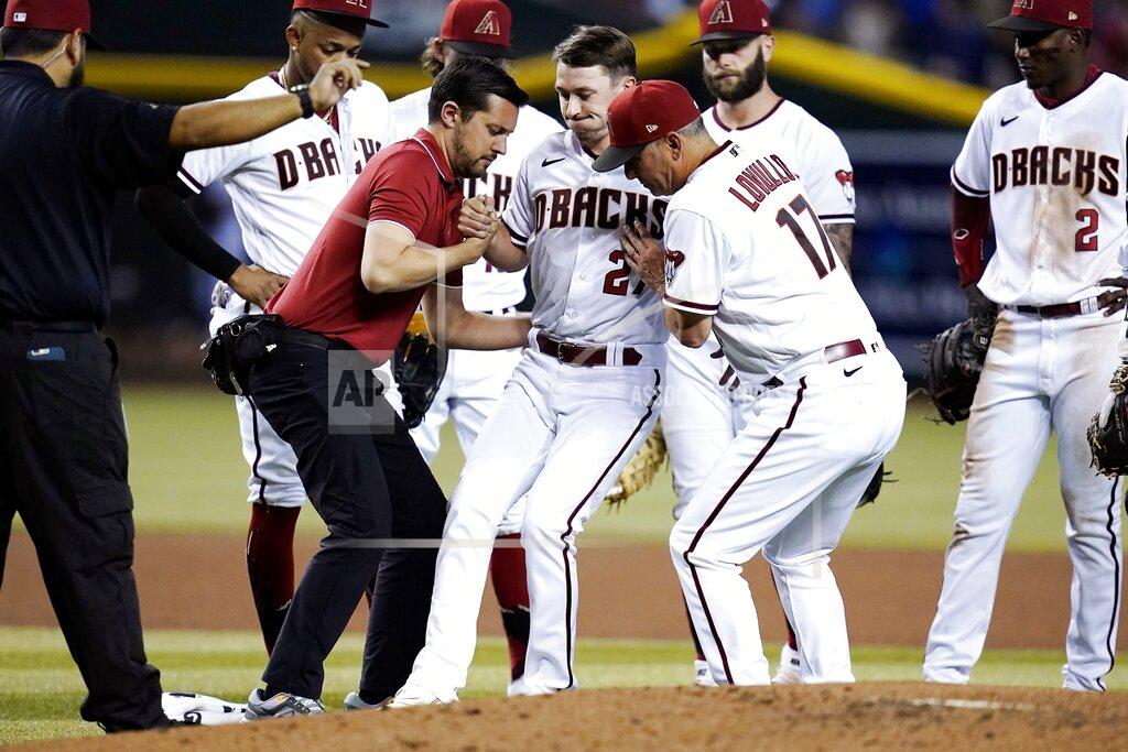 Ross D. Franklin Arizona Diamondbacks starting pitcher Zach Davies, center, is helped up by Diamondbacks assistant athletic trainer Ryne Eubanks, front left, and manager Torey Lovullo (17) after being hit in the shin with a line drive by Kansas City Royals' Bobby Witt Jr. as Diamondbacks shortstop Geraldo Perdomo (2) and other teammates look on during the fourth inning of a baseball game Monday, May 23, 2022, in Phoenix. (AP Photo/Ross D. Franklin)